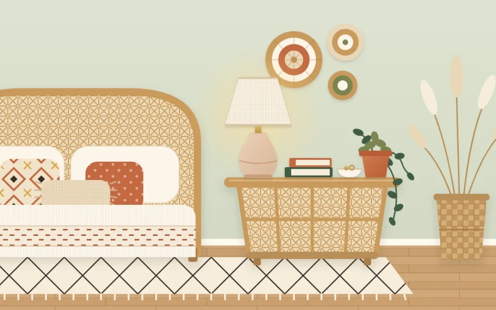 Round rattan bedside table next to a bed with a clay table lamp, a small trailing plant in a terracotta pot, two stacked books and a small ceramic dish