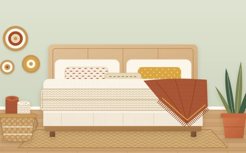 The foot of a bed with a chunky cream knit throw folded across it, a fringed rust throw over one corner and a basket with a rolled blanket